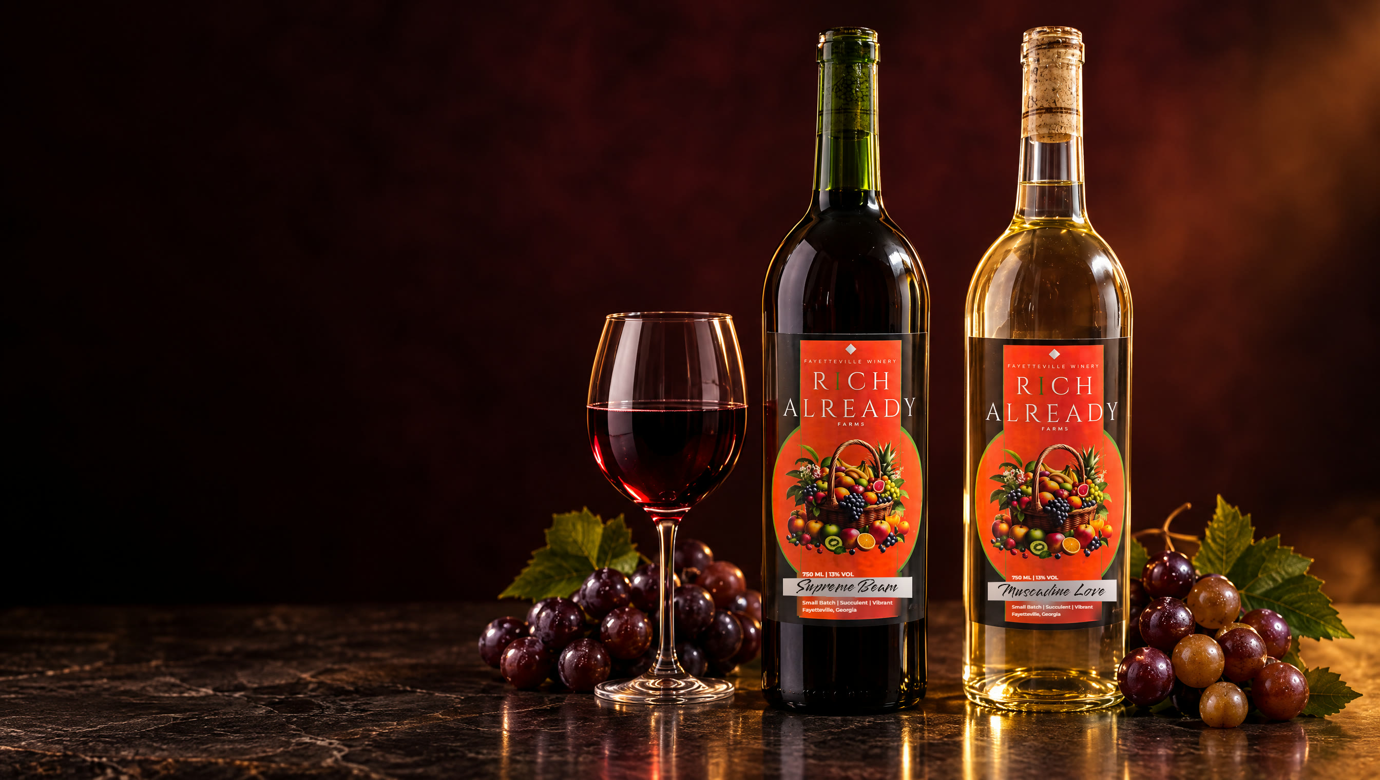 Supreme Beam in green glass and Muscadine Love in clear glass beside a glass of red wine and muscadine grapes, in warm cellar light